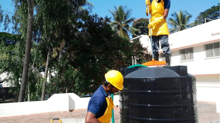 Técnico de Fumigaciones El Triunfo lavando un tanque de agua potable