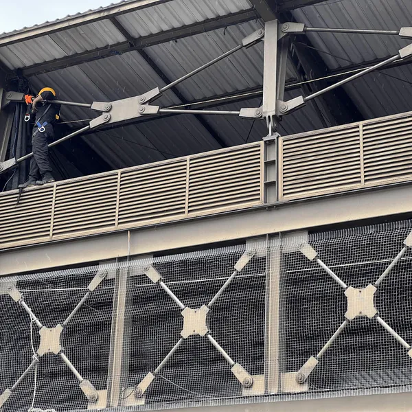 Técnico con arnés instalando malla antipalomas por metro cuadrado en la estructura de un edificio en Bogotá
